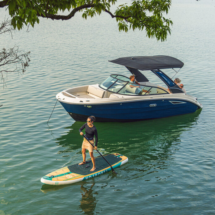 Woman paddleboarding next to an SDX 230