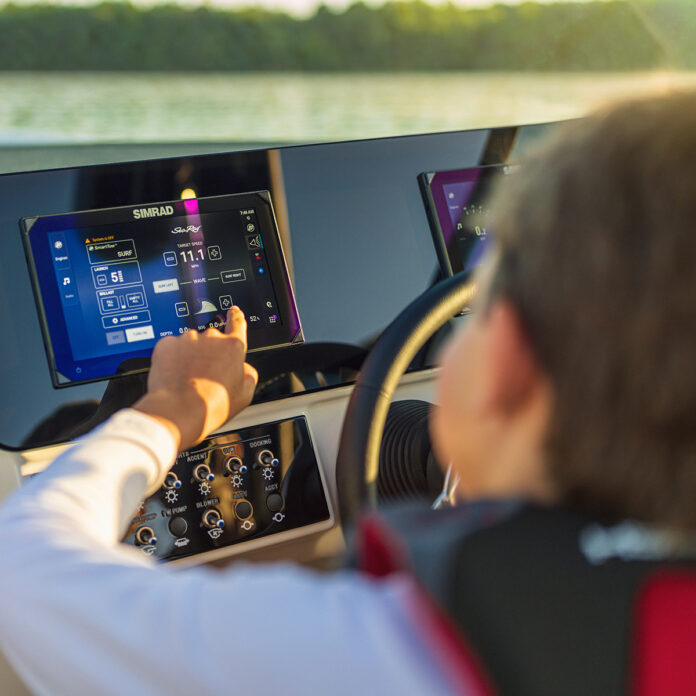 Kid using a touchscreen display at the helm of an SDX 230 Surf