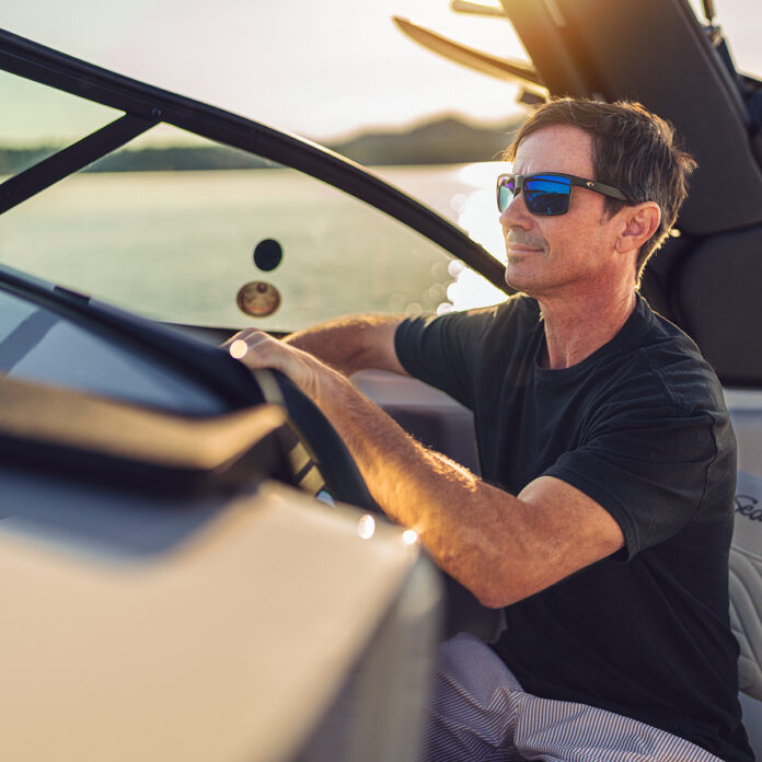 Man at the helm of an SDX 230 Surf at sunset